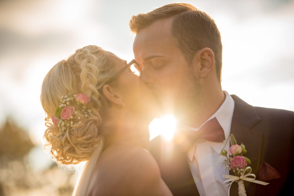 Ein Hochzeitspaar küsst sich im Gegenlicht der Sonne